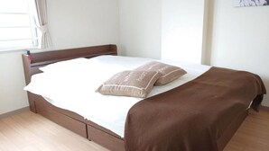 Una cama bien hecha con una manta marrón y dos almohadas con texto, un cabecero de madera y una ventana con cortinas.