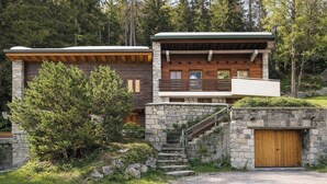 Eine Holzhütte mit Natursteinaußenwand, einer Holzdiele und einer Treppe zu einer zweiten Ebene.