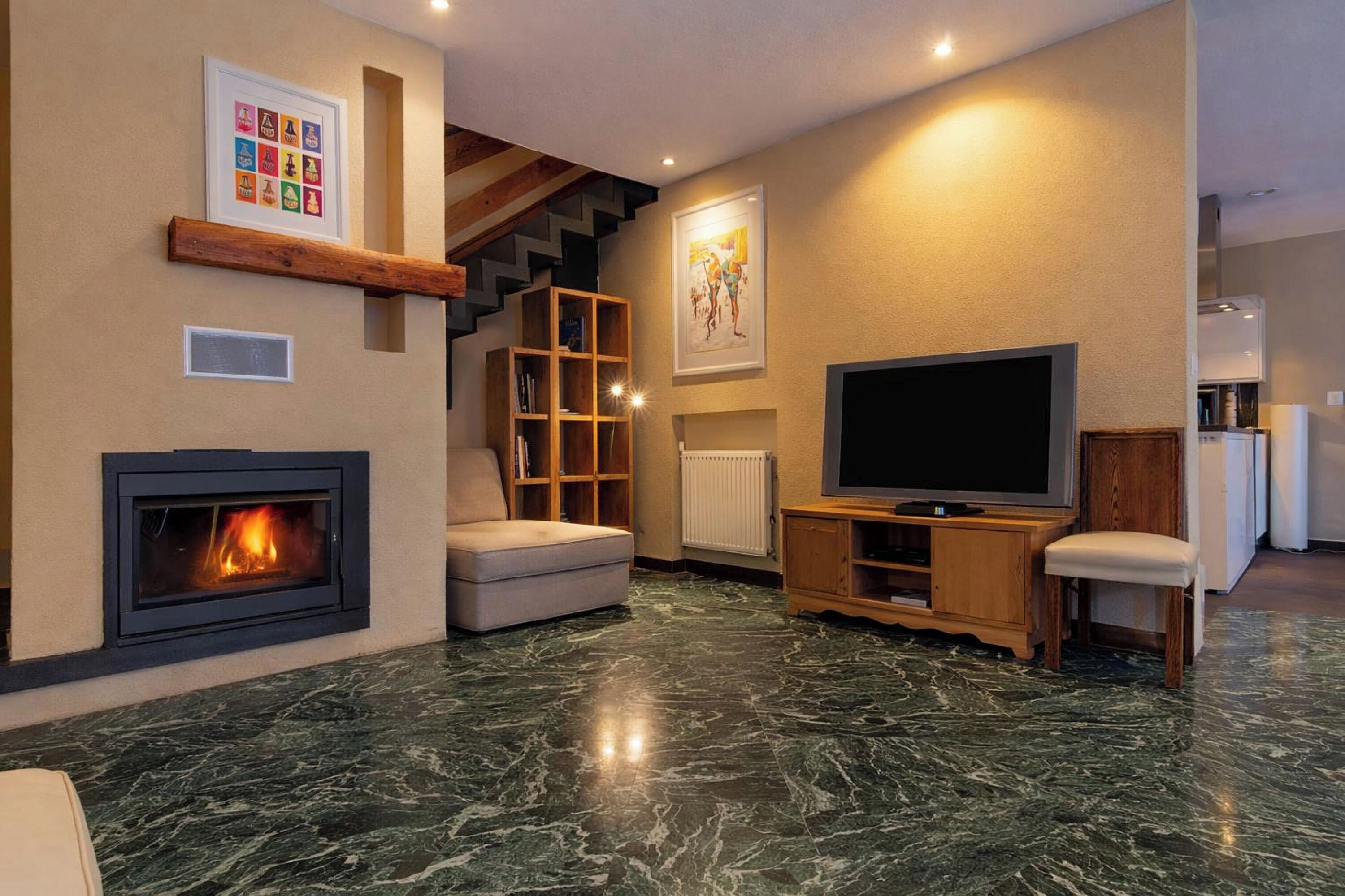 Een woonkamer met een open haard, een televisie, een bank en een trap.