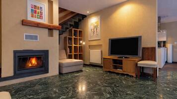 Een woonkamer met een open haard, een televisie, een bank en een trap.