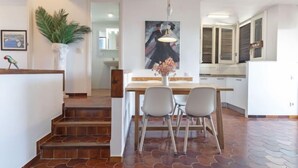 A modern kitchen with a dining area, featuring a staircase, a potted plant, and a painting on the wall. - Apartment Ursula by Interhome (Torredembarra)
