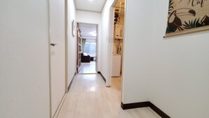 A narrow hallway with a wooden floor, white walls, and a door on the left. A refrigerator is visible on the right wall. - Hokusei Building 6F (Sapporo)