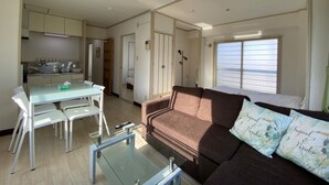 A compact living space with a kitchenette, a dining area, and a sofa with tropical-themed cushions. - Hokusei Building 6F (Sapporo)