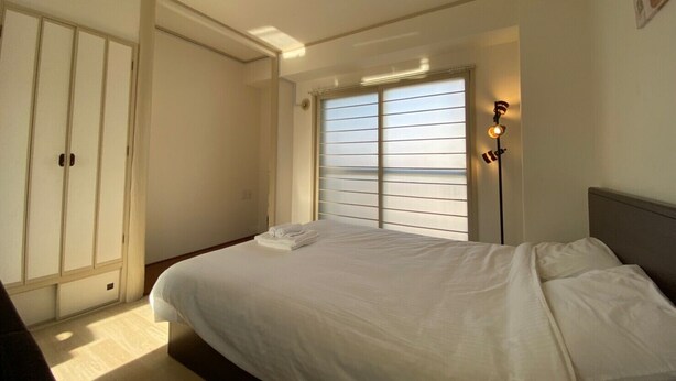 A bedroom with a bed, a wardrobe, and a window with blinds. - Hokusei Building 6F (Sapporo)