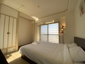 A bedroom with a bed, a wardrobe, and a window with blinds. - Hokusei Building 6F (Sapporo)