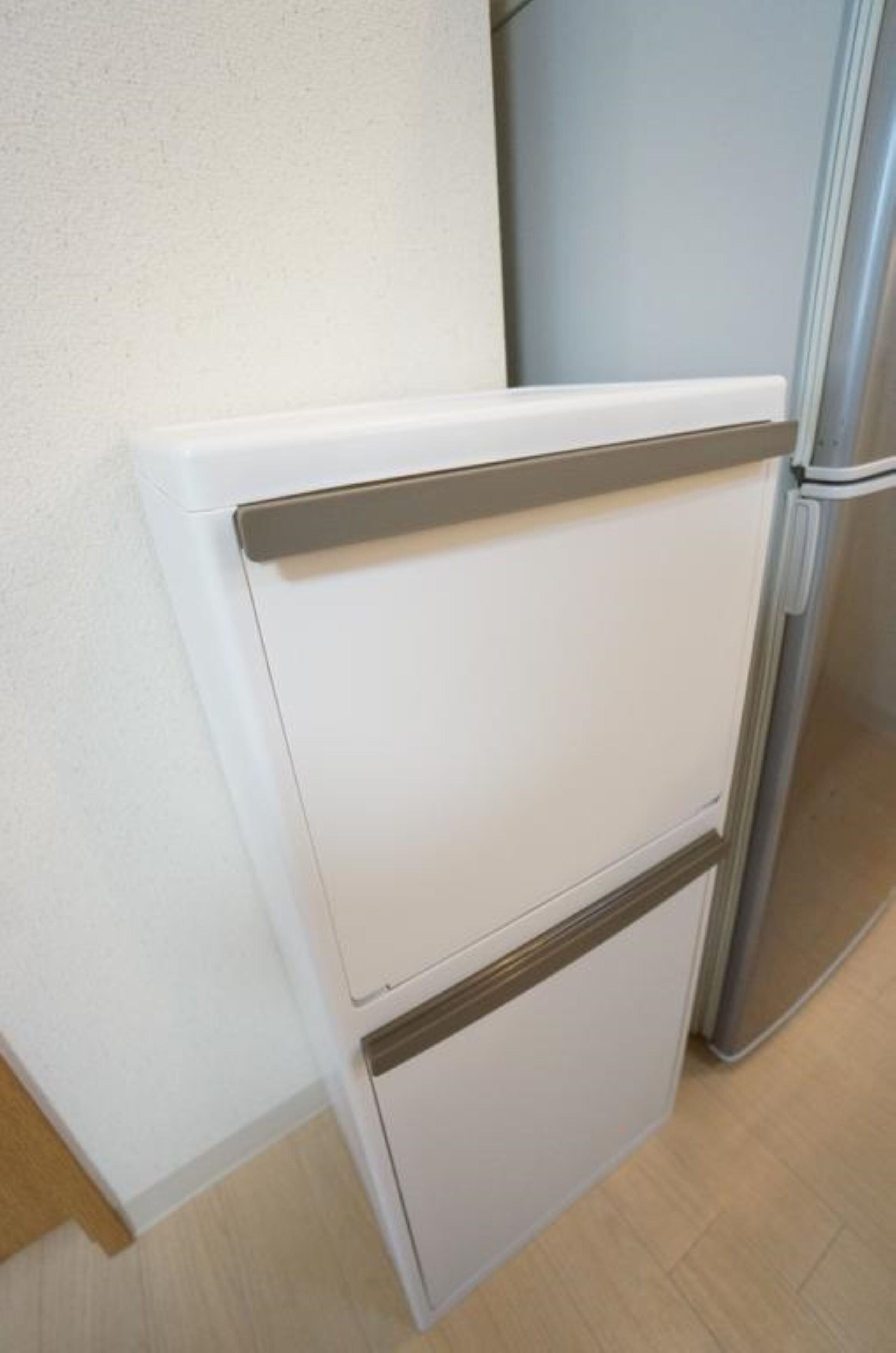 A kitchen with a white refrigerator, a stainless steel oven, and a wooden cabinet.