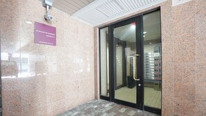 A lobby with a marble floor, a glass door entrance, and a sign above the door. - IK Minami 6JO Residence 901 (Sapporo)