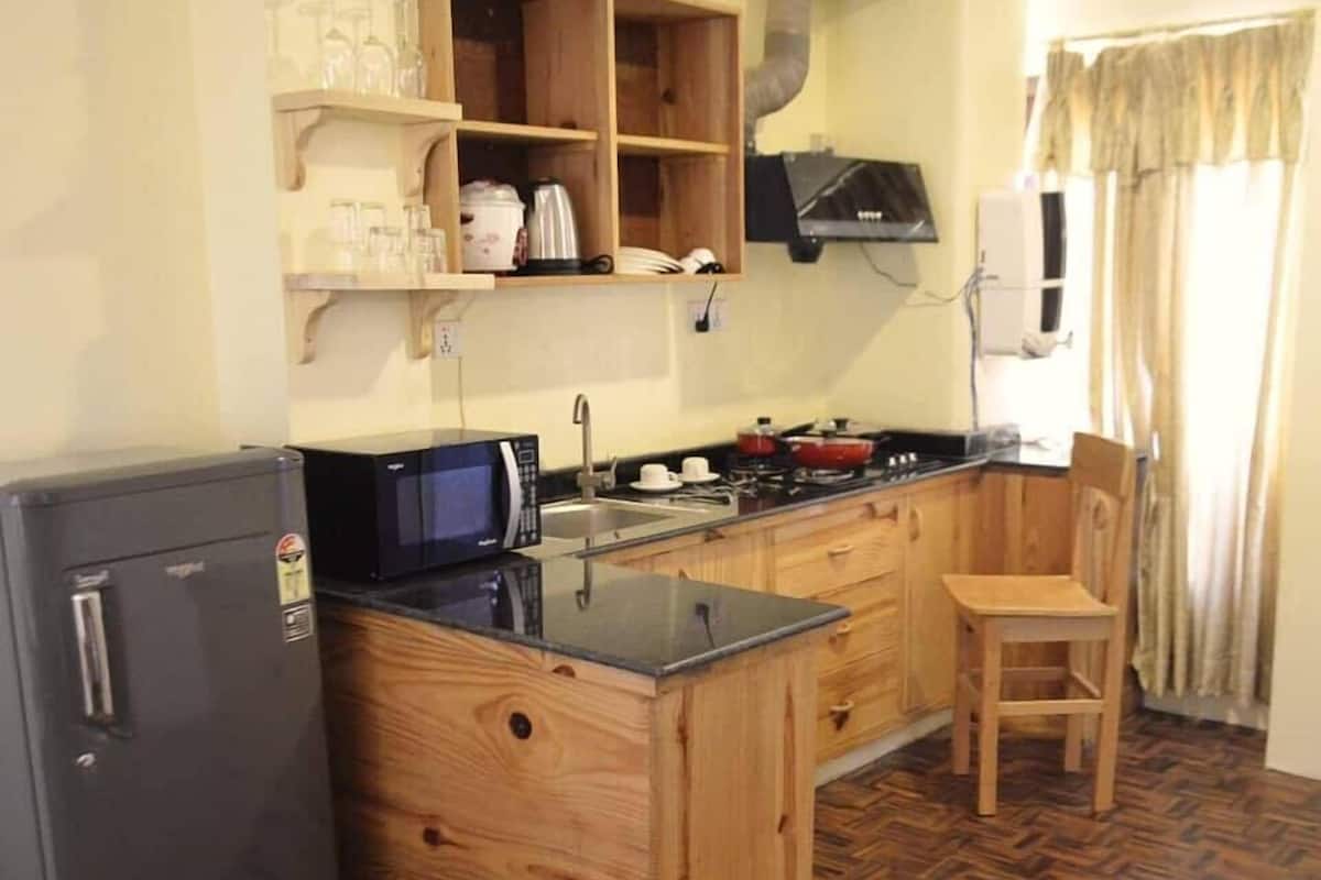 A compact kitchen with a refrigerator, microwave, stove, and wooden cabinets.