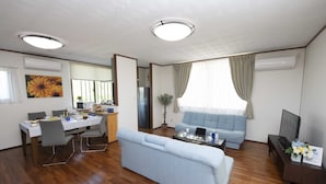 A modern living room with a sofa, dining table, and a TV. - Miyakojima White House Annex (Miyakojima)