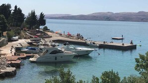 A marina with boats docked, a dock extending into the water, and a clear view of the surrounding landscape.