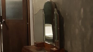 Una habitación con tocador de madera, un espejo, una puerta y un tapete a rayas.