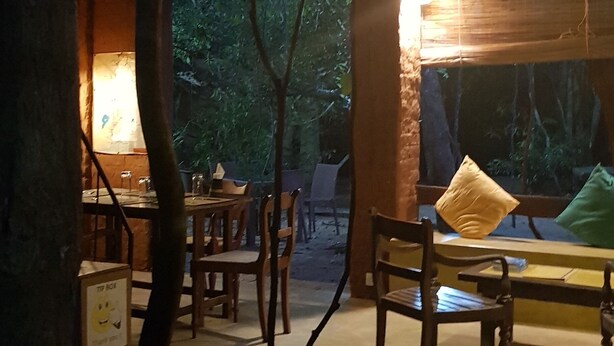 Un interior rústico de madera con techo de paja, muebles de madera y faroles colgantes.