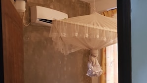 Un dormitorio con cama, mosquitero y aire acondicionado instalado en la pared.