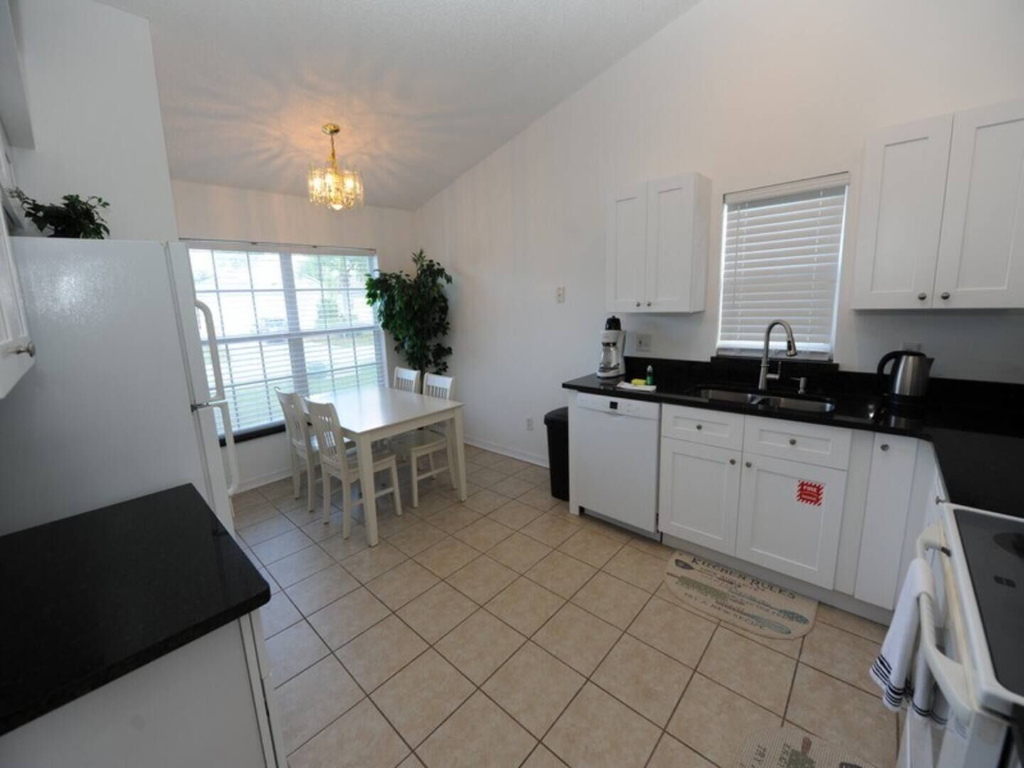 A compact kitchen with white cabinets, a dining table, and a black countertop.