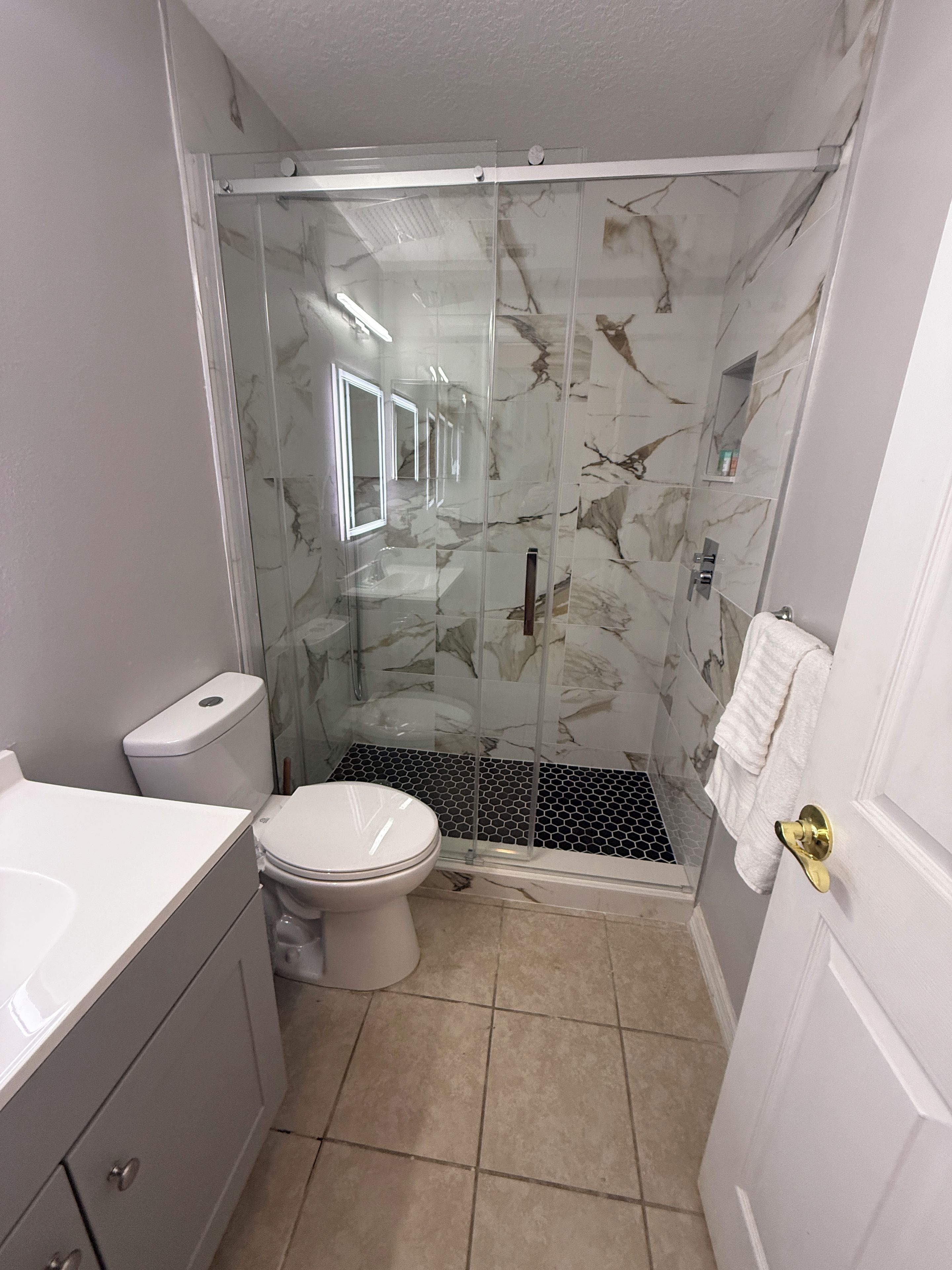 Ein Badezimmer mit Duschkabine, Toilette und Waschbecken.