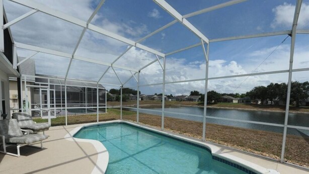 A swimming pool with a clear view of the surrounding area, including a covered patio and a view of a body of water. - Holiday Hideout by Paradise Resort Vacations (Clermont)