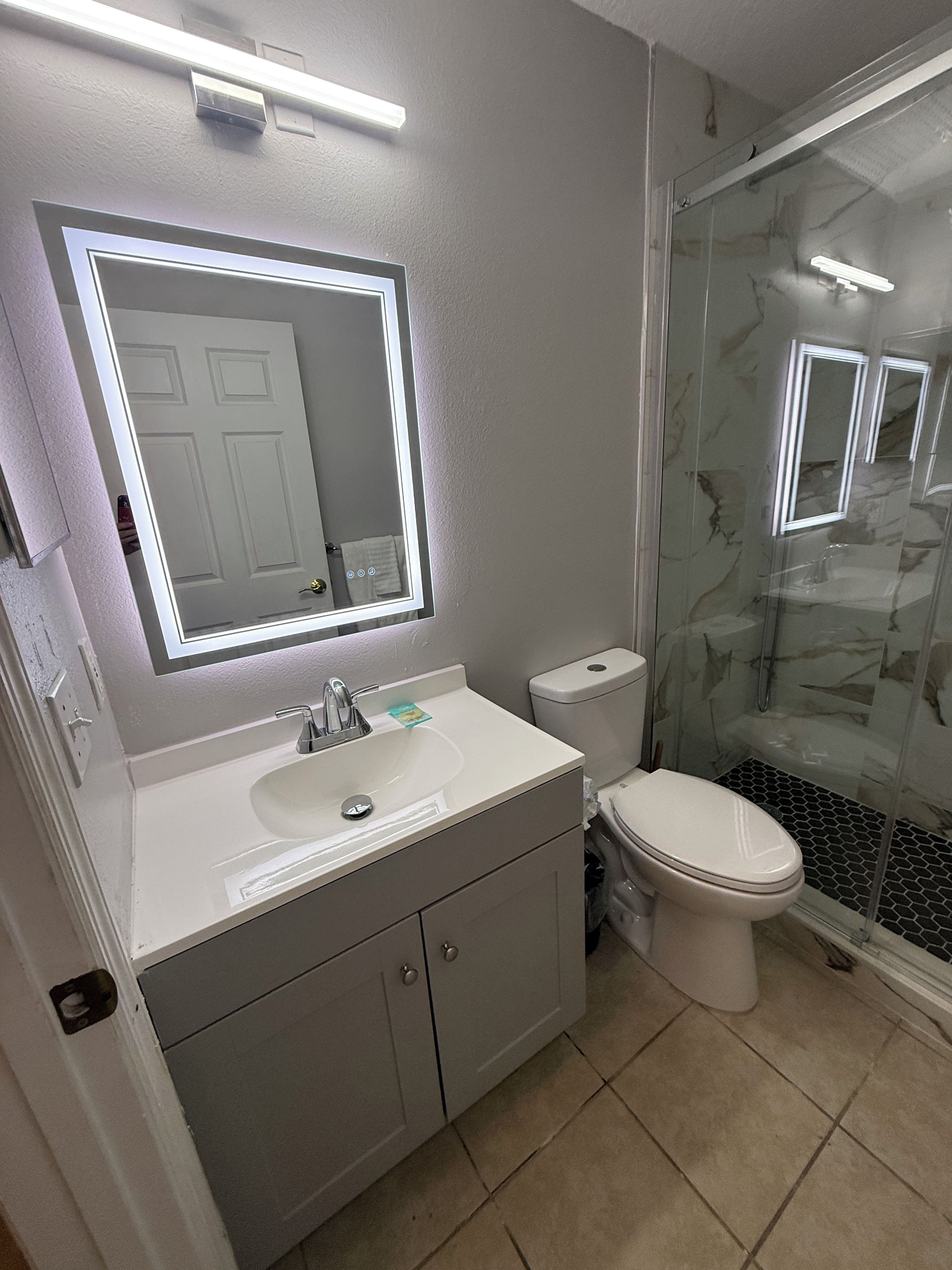 Un baño con lavamanos, espejo y retrete blancos.