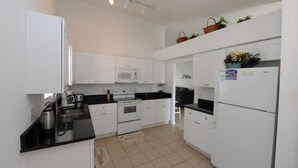 A modern kitchen with white cabinets, a black countertop, a microwave, an oven, and a refrigerator. - Holiday Hideout by Paradise Resort Vacations (Clermont)
