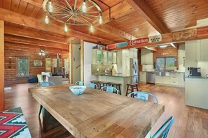 Un interior de madera espacioso con una gran mesa de comedor, una zona de cocina y un letrero que indica leche fresca.
