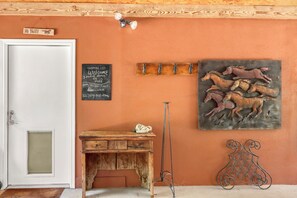 Une pièce avec un bureau en bois, un tableau noir sur lequel est inscrite une liste de courses, un tableau représentant un cheval et une sculpture en métal.