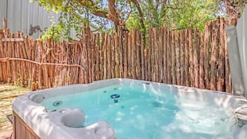 A hot tub in a backyard with a wooden fence and trees.