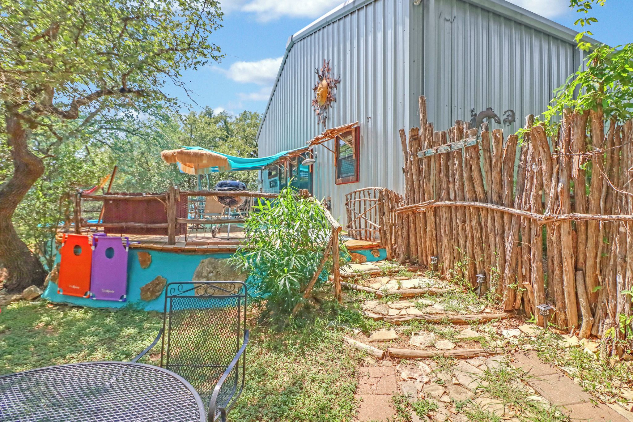 A backyard with a play area, a barbecue grill, and a rustic wooden fence.