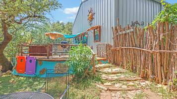 A backyard with a play area, a barbecue grill, and a rustic wooden fence.