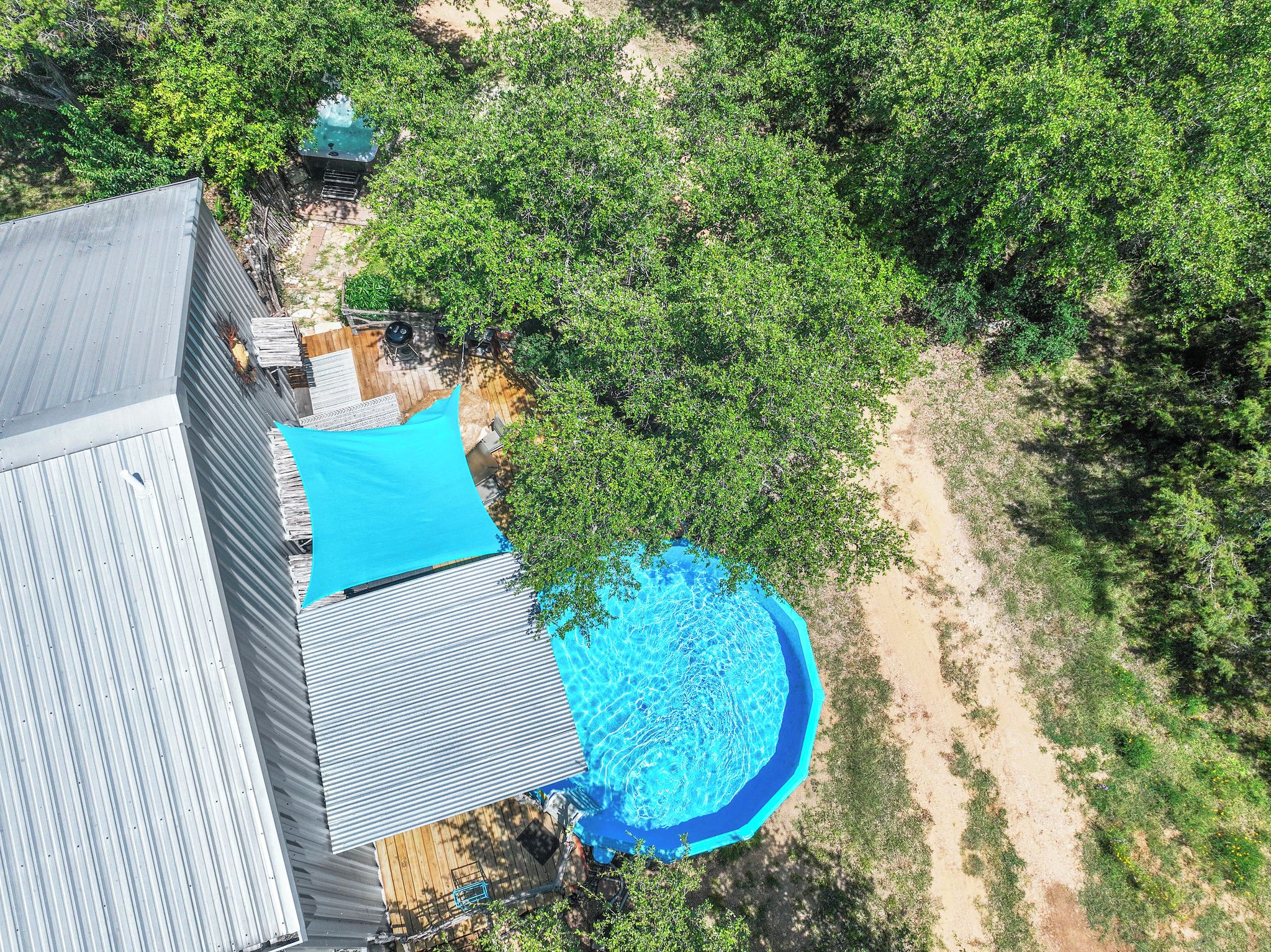 A residential area with a swimming pool, a wooden deck, and a metal roof.