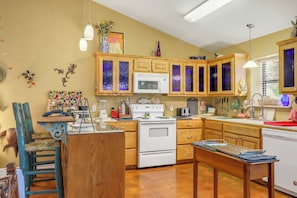 A kitchen with wooden cabinets, a white stove, a microwave, and various kitchen appliances.