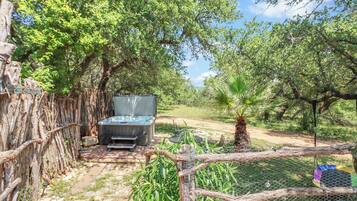 A fenced outdoor area with a barbecue grill, a hammock, and a small pool.
