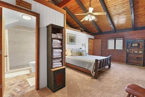 Un dormitorio con techo de madera, una cama, un estante con toallas dobladas, una ducha y un letrero que indica que no se permiten parejas en la ducha.