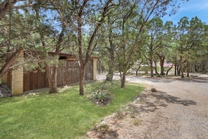 A fenced yard with a wooden cabin, a gravel path, and a small garden area.