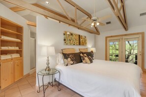 Un dormitorio con una cama grande, un armario de madera y un ventilador de techo.