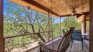 Eine Holzterrasse mit einer Schaukelstuhlsitzgruppe, einem Tisch und Stühlen.