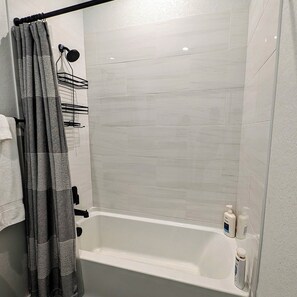 Un baño con una bañera blanca, una cortina de ducha y un perchero.
