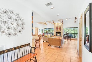 Un salón amplio con chimenea, ventanas grandes y una zona de comedor con muebles de madera.