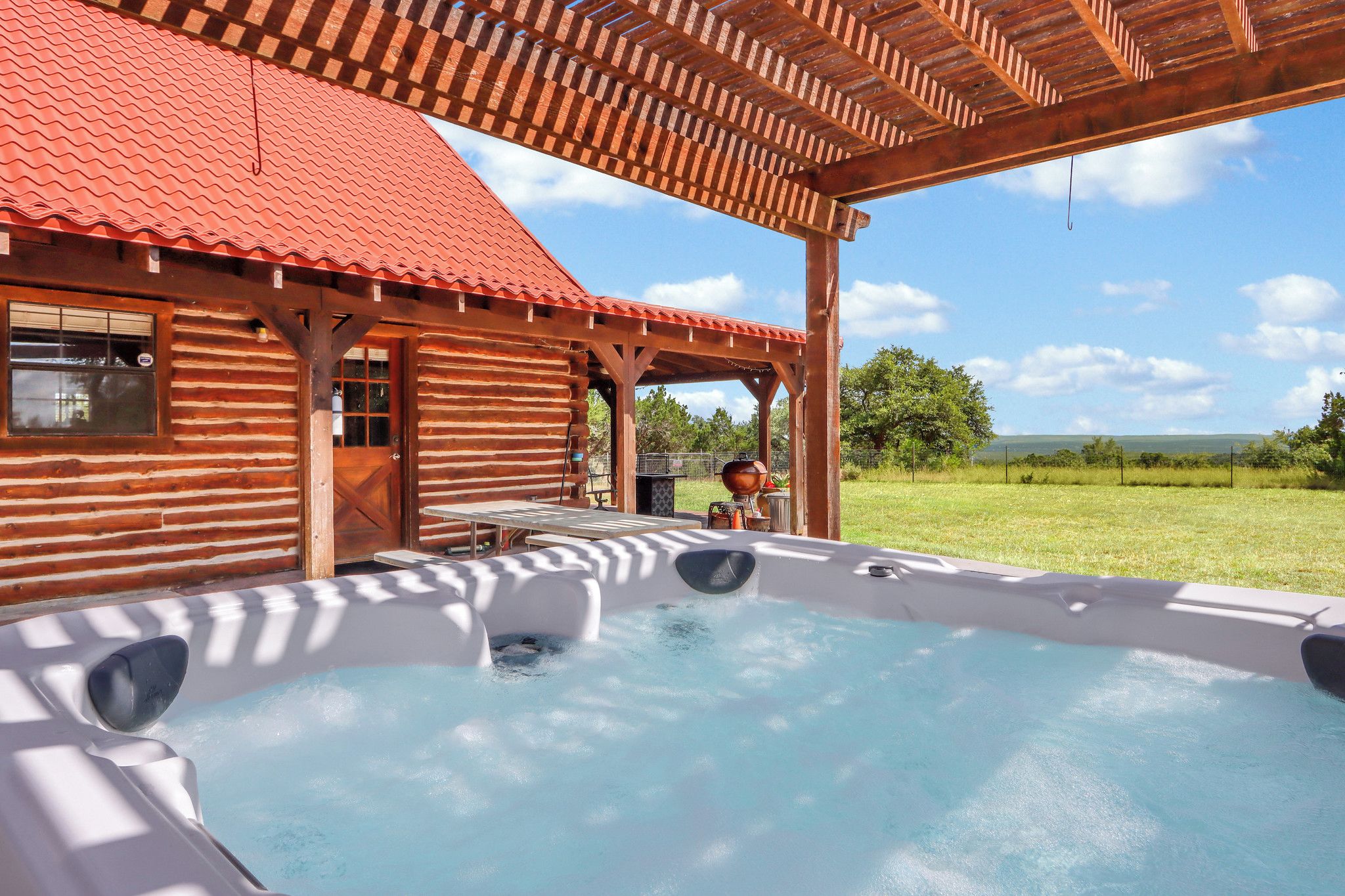 A wooden cabin with a hot tub and a covered patio area.