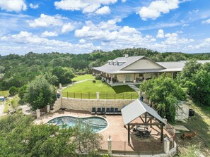 Una casa grande con piscina, un patio cubierto y un césped cuidado.