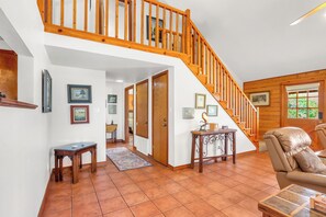 A spacious living area with a wooden staircase, a fireplace, and a large window.