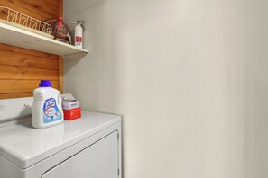 A laundry area with a washing machine, a bottle of laundry detergent, and a box of detergent on the counter.