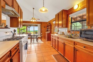 A spacious kitchen with wooden cabinets, a gas stove, a sink, and a dining area with chairs.