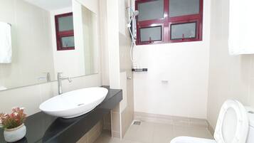 A bathroom with a white sink, a mirror, a window with a red frame, and a toilet.
