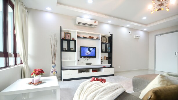 Een moderne woonkamer met een flatscreen televisie, witte meubels en decoratieve objecten.