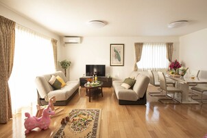 A living room with two sofas, a coffee table, a TV, and a dining area with chairs and a table.