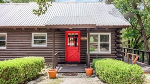 Una cabaña de troncos con puerta roja, un porche y un letrero que dice 'The Jacks'.