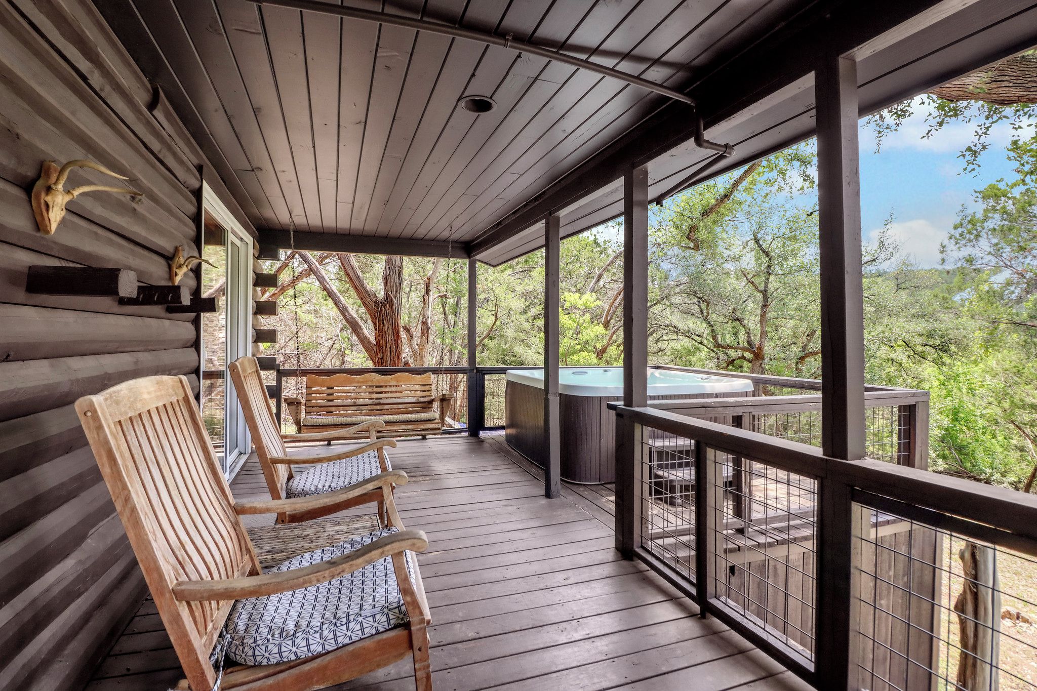 A covered porch with wooden chairs and a hot tub.