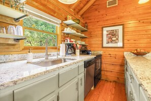 Una cocina con encimera de granito, electrodomésticos de acero inoxidable y paredes de madera.