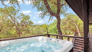 Un jacuzzi en una terraza de madera con vistas a árboles y al cielo.