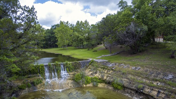 Un paisaje natural con cascada, estanque y vegetación circundante.