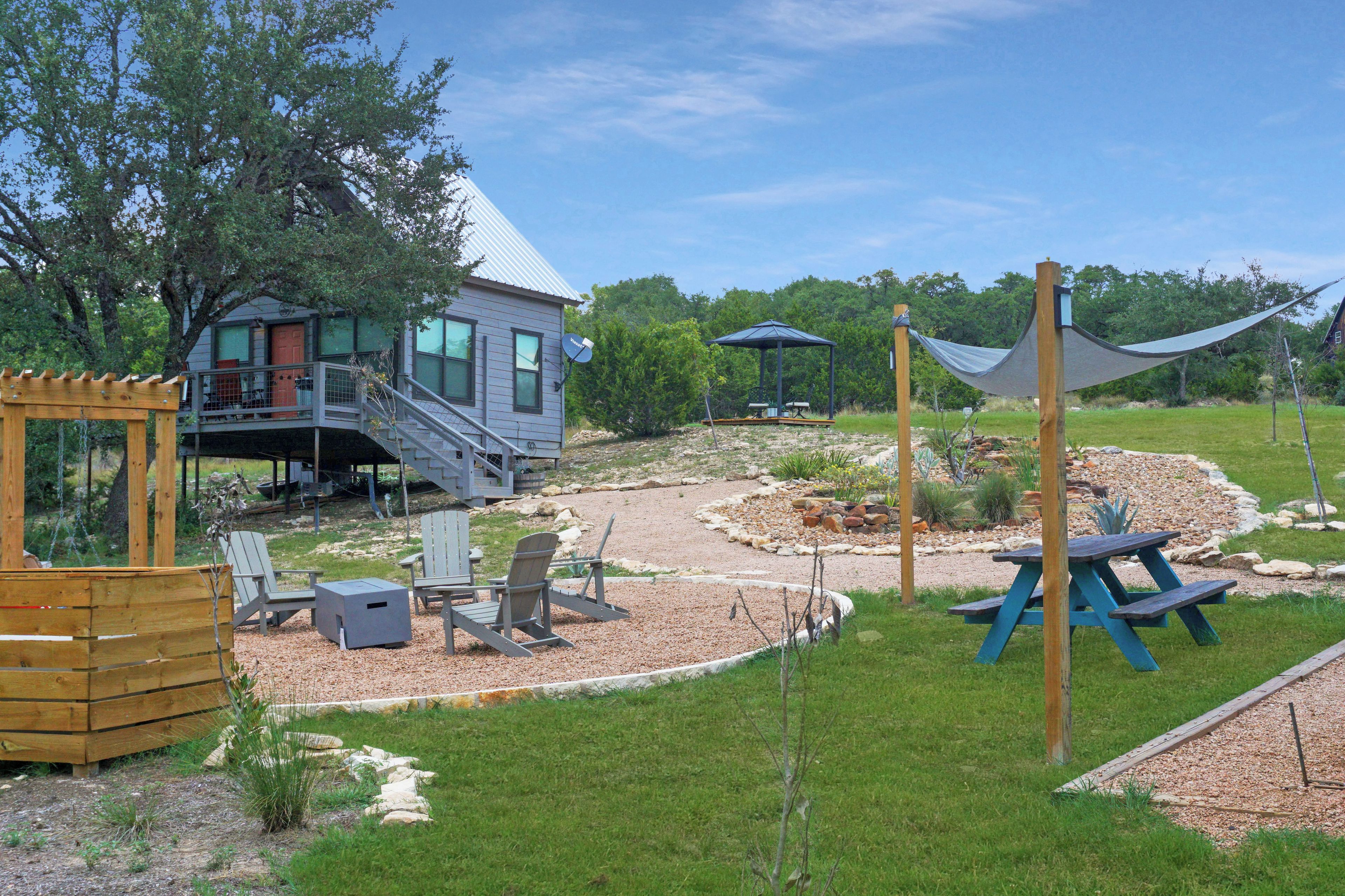 Una casa con terraza, mobiliario exterior y un jardín con mesa de picnic.